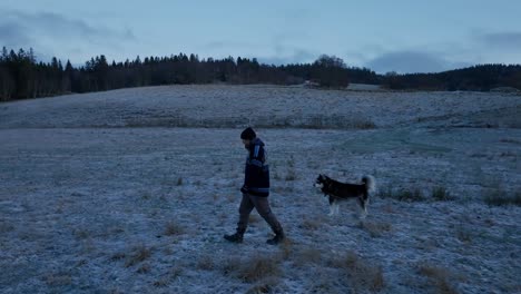 Indre-Fosen,-Trondelag-County,-Norway---In-November,-a-Man-Walks-Alongside-His-Dog-Through-the-Farm---Tracking-Shot