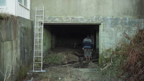A-Man-is-Removing-the-Soil-From-an-Abandoned-Building---Static-Shot