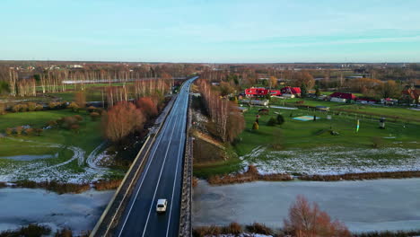 Cars-driving-on-bridge-over-frozen-river,-aerial-drone-view