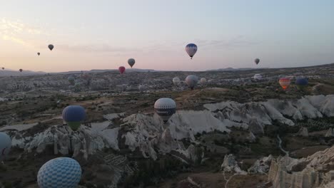 Drone-view-before-sunrise-of-a-colorful-hot-air-balloon-inflated-over-a-wide-plain,-a-very-famous-tourist-attraction-in-Cappadocia,-Turkey