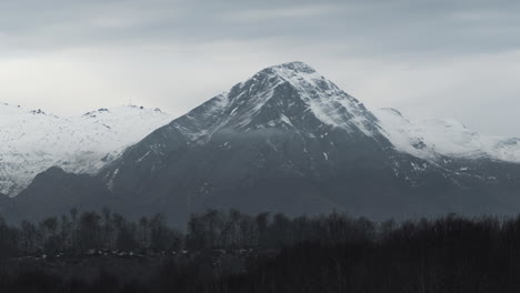 Timelapse-clouds-covering-Snow-Capped-Peaks-winter-forest-cloudy-slow-pan-right