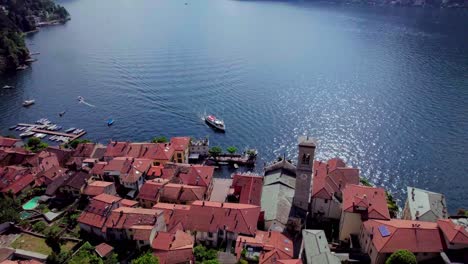 Boat-docking-at-Torno-village-on-Lake-Como,-Aerial-backward-reveal,-Italy