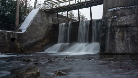 Timelapse-of-Alton-Mill-dam-sluice-river-waterfall-in-winter,-Canada