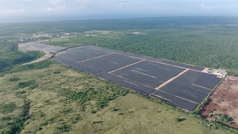 Aerial-View-Of-Solar-Panels-Producing-Energy-In-Green-Field,-Parque-Solar-Fotovoltaico-Cumayasa-In-Dominican-Republic---Drone-Shot