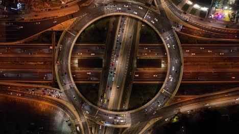 Drone-flight-over-a-circular-highway-and-multiple-levels-at-night