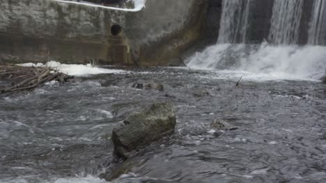 Water-Flowing-Past-A-River-Rock,-Beautiful-Winter-Waterfall-Landscape
