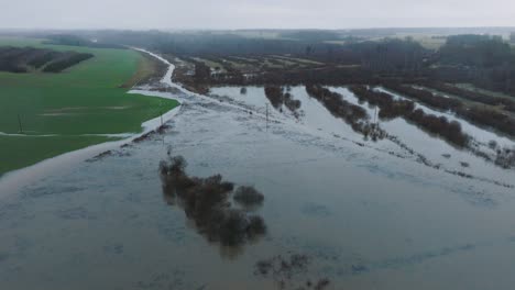 Luftaufnahme-Von-Hochwasser-Im-Frühling,-Überschwemmung-Des-Alande-Flusses,-Braunes-Und-Schlammiges-Wasser,-Landwirtschaftliche-Felder-Unter-Wasser,-Bewölkter-Tag,-Weite-Drohnenaufnahme,-Die-Sich-Vorwärts-Bewegt