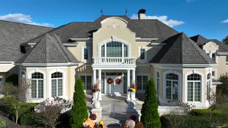 Luxurious-house-with-fall-decorations-and-manicured-garden-under-a-clear-sky