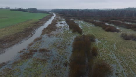 Aerial-establishing-view-of-high-water-in-springtime,-Alande-river-flood,-brown-and-muddy-water,-agricultural-fields-under-the-water,-overcast-day,-wide-drone-dolly-shot-moving-right-low