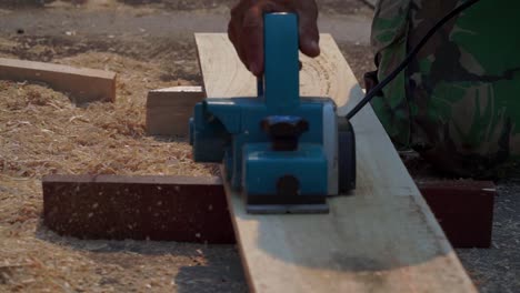Carpenter-holding-planer-machine-and-smoothing-a-plank