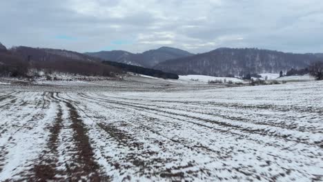 Schnelle-Luftaufnahme-über-Schneebedeckten-Feldern,-Berggipfeln,-Hintergrund,-Bewölkter-Tag