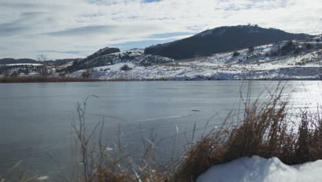 Invierno-Lago-De-Montaña-Congelado-Cubierto-De-Nieve-Soleado-Día-Nublado-Panorámica-Izquierda