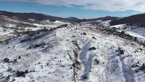 Antena-Lenta-Sobre-Llanuras-Montañosas-Cubiertas-De-Nieve-Soleado-Día-De-Invierno