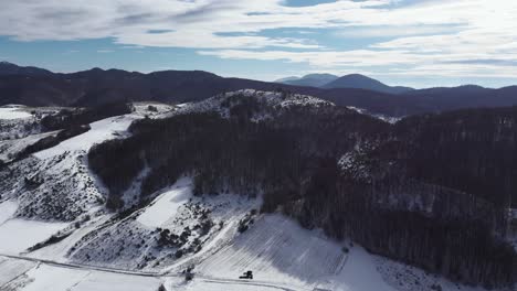 Slow-Aerial-over-snow-covered-mountain-forest-plains-sunny-Winter-Day