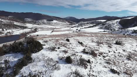Drone-Sobre-Montañas-Campos-Rurales-Llanuras-Cubiertas-De-Nieve-Invierno-Día-Soleado-Cielo-Azul