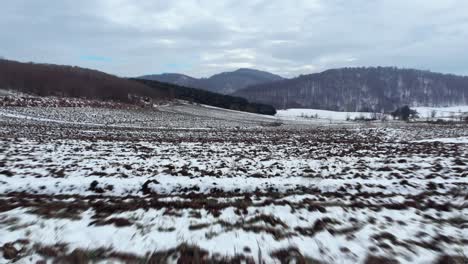 Fast-Aerial-over-snow-covered-mountain-field-plains-cloudy-winter-Day