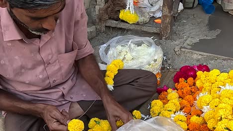 front-view,-a-shopkeeper-is-making-fresh-flower-garlands-on-the-street-road