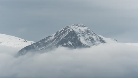 Timelapse-clouds-covering-Snow-Capped-mountain-peaks-winter-cloudy-zoom-shot
