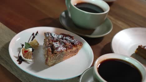 Pecan-pie-dessert-on-a-cafe-restaurant-table,-accompanied-by-cups-of-coffee