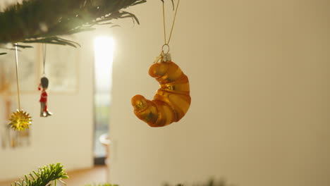 Goldenes-Croissant-Ornament,-Das-An-Einem-üppigen-Weihnachtsbaum-Baumelt