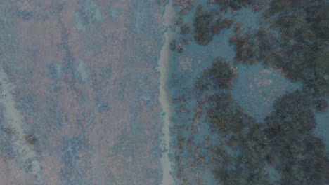Aerial-establishing-view-of-high-water,-Durbe-river-flood,-brown-and-muddy-water,-agricultural-fields-under-the-water,-overcast-winter-day-with-light-snow,-birdseye-drone-shot-moving-forward