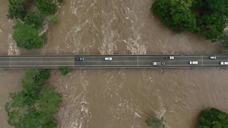 Aerial-views-above-cars-driving-over-the-Barron-River-bridge-at-Caravonica-after-the-extreme-flooding-caused-by-Cyclone-Jasper,-Cairns