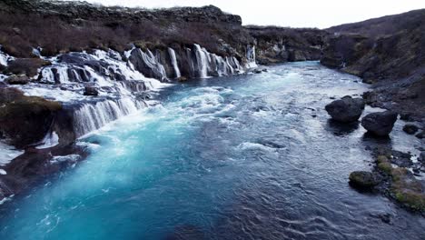 Waterfall-cascade-Hraunfossar-in-western-Iceland,-aerial-dolly