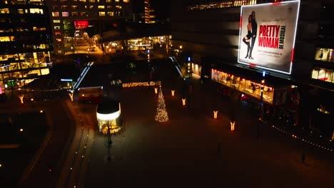 Drone-flying-towards-decorative-Christmas-tree-on-Jaarbeursplein,-Utrecht,-the-Netherlands-at-night