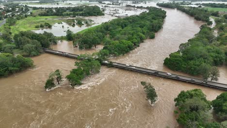 Cars-driving-over-the-Barron-River-bridge-at-Caravonica-with-major-flooding-in-Cairns,-Australia