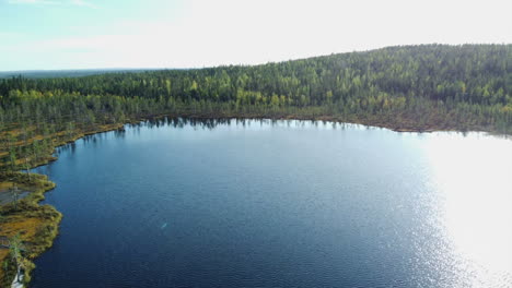 Aerial-descends-to-surface-of-large-pond-in-autumn-boreal-forest