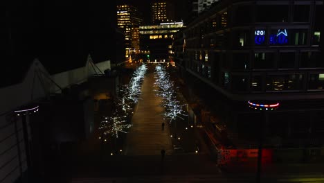 Jib-down-of-festively-decorated-pathway-between-buildings-at-night
