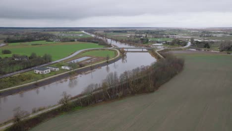 Aerial-establishing-view-of-high-water-in-springtime,-Barta-river-flood,-brown-and-muddy-water,-overcast-day,-wide-drone-shot-moving-forward