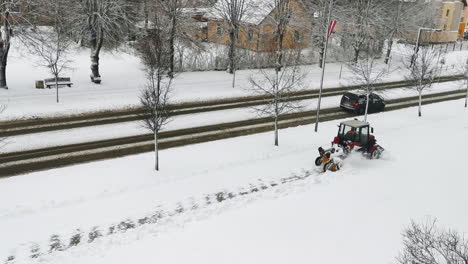 Tractor-clean-snow-from-walkway-with-plough-sweeping-brush