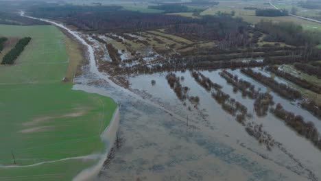 Aerial-establishing-view-of-high-water-in-springtime,-Alande-river-flood,-brown-and-muddy-water,-agricultural-fields-under-the-water,-overcast-day,-wide-birdseye-drone-shot-moving-forward