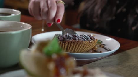 Woman-eats-a-dessert-and-drinks-coffee-in-a-cafe,-women-hands-eating-pie-dessert-with-a-spoon