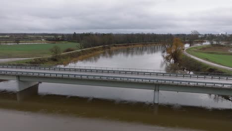 Aerial-establishing-view-of-high-water-in-springtime,-Barta-river-flood,-brown-and-muddy-water,-overcast-day,-wide-drone-shot-moving-forward-over-the-concrete-bridge