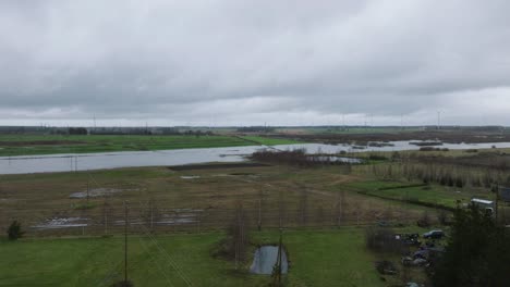 Aerial-establishing-view-of-high-water-in-springtime,-Alande-river-flood,-brown-and-muddy-water,-agricultural-fields-under-the-water,-overcast-day,-wide-drone-shot-moving-forward