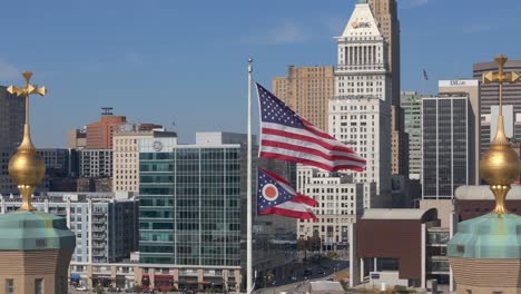 American-Flag-and-Ohio-Flag-against-Cincinatti-skyline-backdrop,-Aerial-drone-orbit