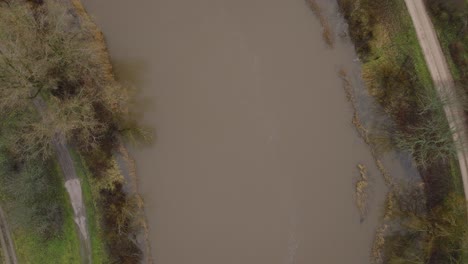 Aerial-birdseye-view-of-high-water-in-springtime,-Barta-river-flood,-brown-and-muddy-water,-overcast-day,-wide-drone-shot-moving-forward
