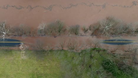 Aerial-top-down-shot-of-muddy-flooded-street-in-suburb-area-with-dirty-river-water-after-heavy-rain-in-USA