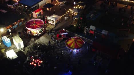 Illuminated-Christmas-fairground-event-in-neighbourhood-pub-car-park-at-night-aerial-view