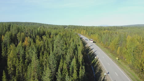 Aerial-follows-tour-bus-on-highway-through-flat-northern-boreal-forest