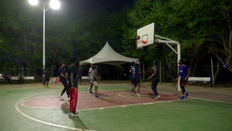 Low-angle-of-black-team-playing-basketball-at-night-in-africa