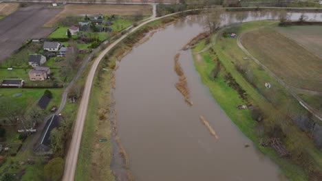 Aerial-establishing-view-of-high-water-in-springtime,-Barta-river-flood,-brown-and-muddy-water,-overcast-day,-wide-birdseye-drone-shot-moving-forward