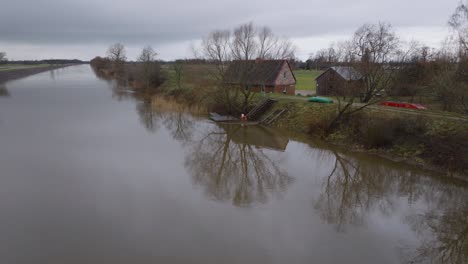 Aerial-establishing-view-of-high-water-in-springtime,-Barta-river-flood,-brown-and-muddy-water,-overcast-day,-remote-house-on-the-bank-of-the-river,-wide-drone-shot-moving-forward-low