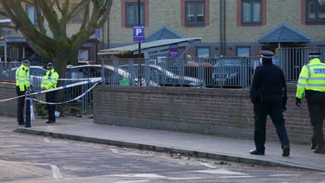 Metropolitan-police-officers-guard-the-entrance-to-a-property-at-a-gun-crime-murder-scene-cordon-as-forensic-officers-stand-in-the-doorway-of-a-home-in-Hackney