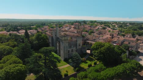 Far-orbiting-shot-of-Chateau-de-Pouzilhac-with-a-surrounding-city