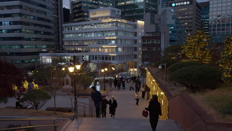 Korean-People-Tavel-at-Myeongdong-Cathedral-Park-at-Sunset-with-Seoul-Office-Skyscraperper-Buildings-in-backgound