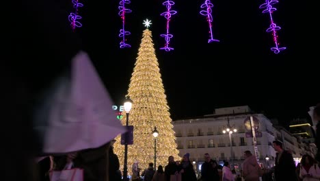 Menschen-Gehen-An-Einer-Beleuchteten-Weihnachtsbauminstallation-Vorbei,-Die-Mit-Goldenen-LED-Lichtern-Für-Die-Weihnachtsfeierlichkeiten-Und-Feiertage-Auf-Dem-Platz-Puerta-Del-Sol-In-Madrid-Geschmückt-Ist