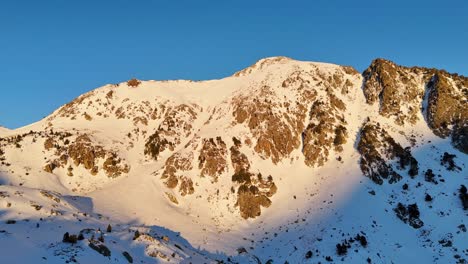 Circular-drone-footage-of-snowy-mountains-with-a-golden-sun-in-the-Pyrenees-mountains